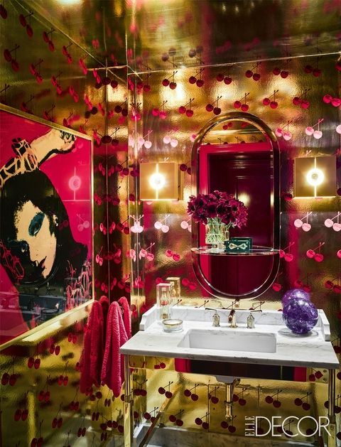 a bathroom decorated in red and gold with pink flowers on the wall, mirror, sink and vanity