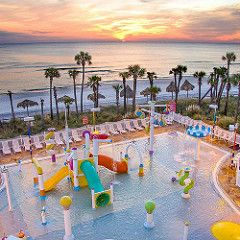 an outdoor play area at the beach with slides and water toys in front of the ocean