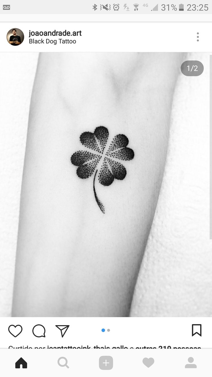 a small four leaf clover tattoo on the left inner arm, with text below it