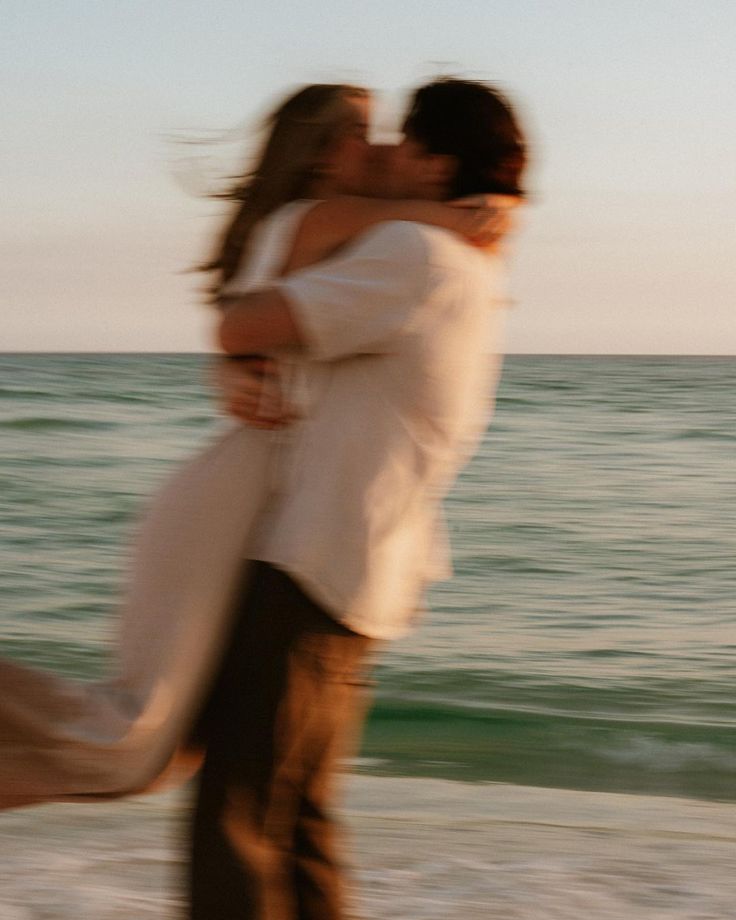 a man and woman kissing on the beach