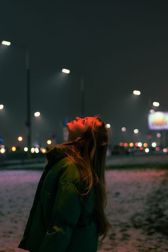 a woman standing in the sand at night with her eyes closed and head turned to the side