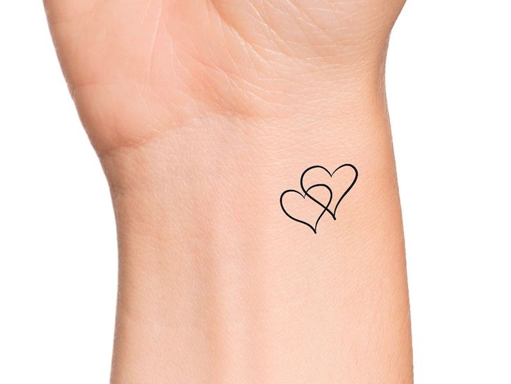 a heart tattoo on the wrist with two hearts in it's center and an arrow at the bottom