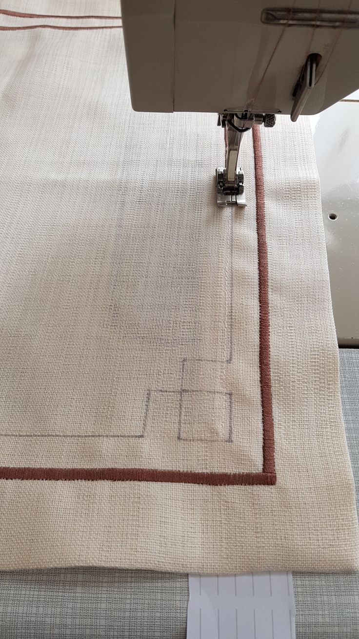 the sewing machine is working on the fabric that has been stitched together with red thread