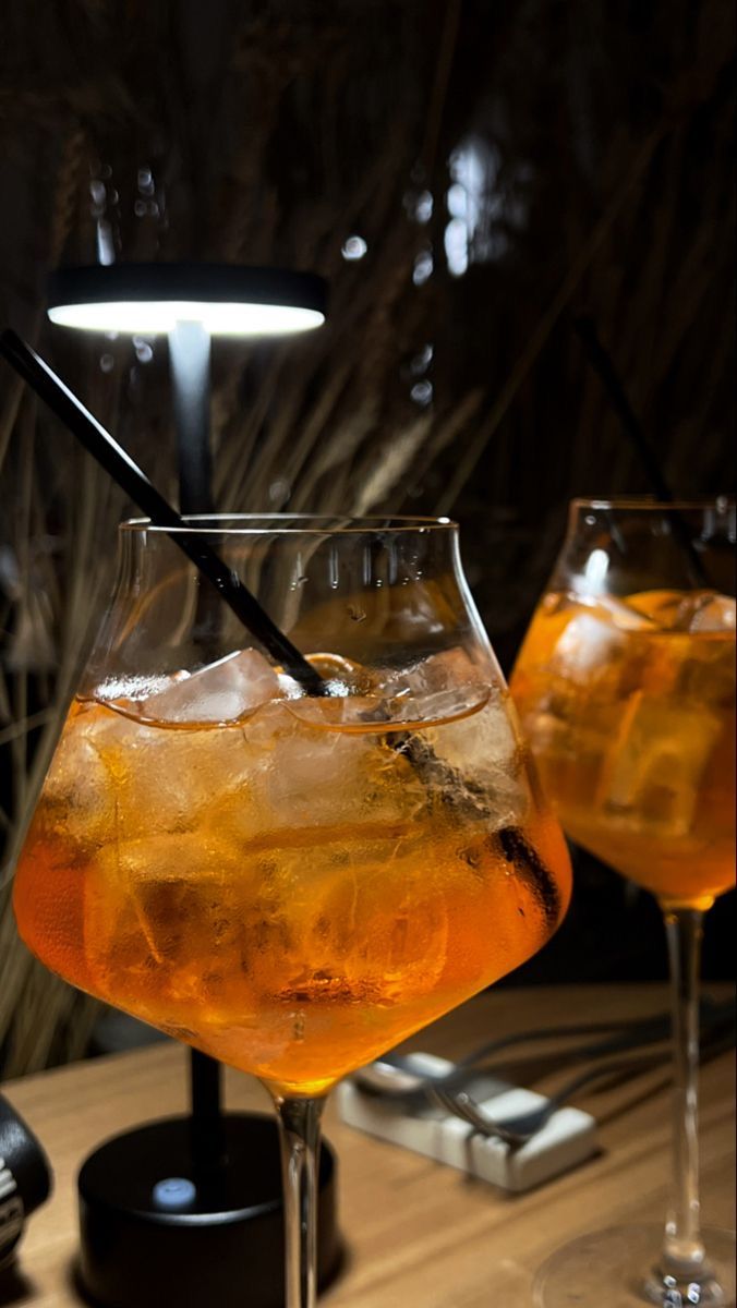 two glasses filled with drinks sitting on top of a wooden table