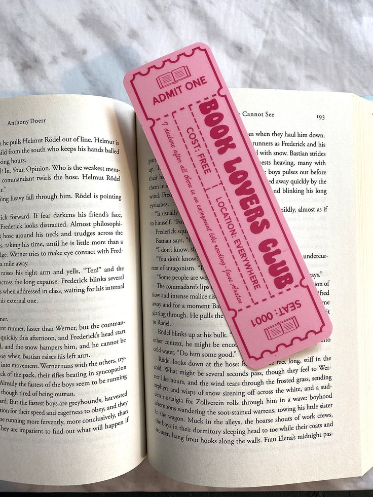 an open book with a pink ticket sitting on top of it