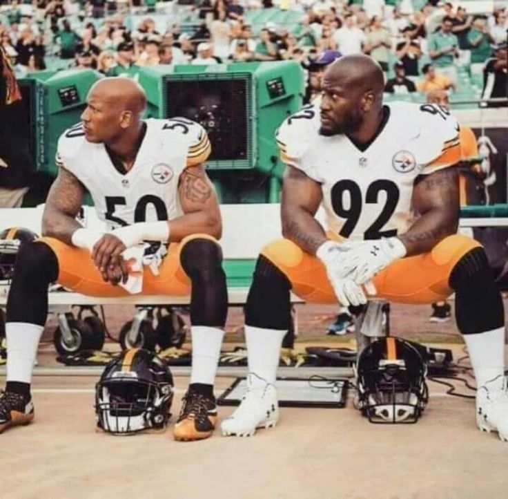 two football players are sitting on the sidelines