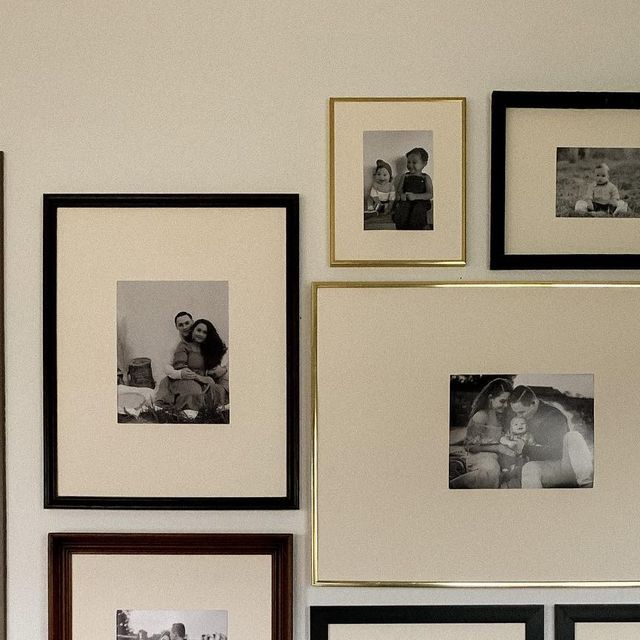 black and white photos are hung on the wall next to framed family pictures in frames