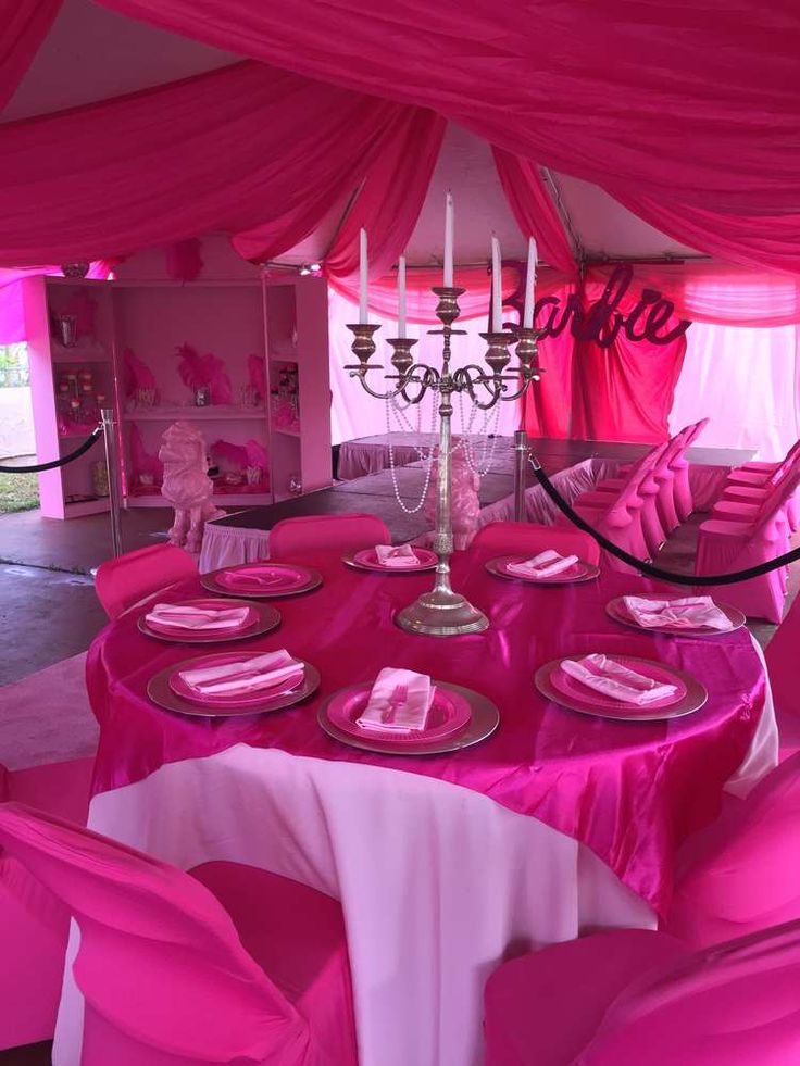 a table set up for a party with pink linens and place settings on it