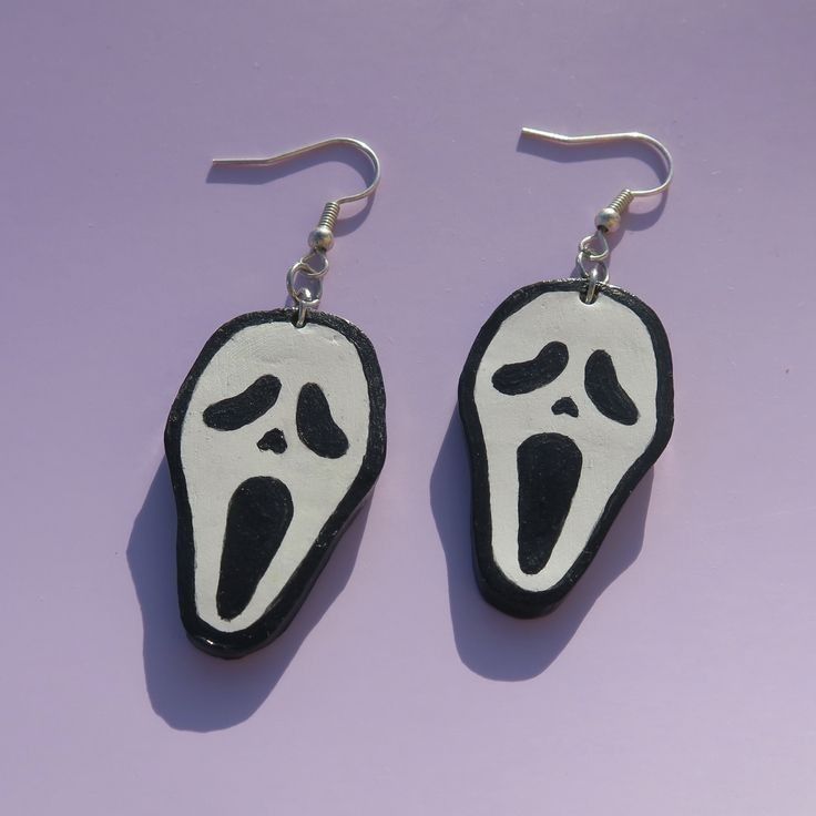 two pairs of earrings with black and white designs on them, one has a ghost face hanging from it's earwires