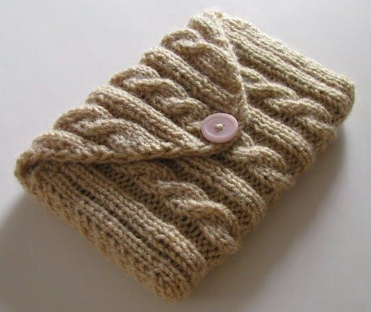 a knitted cell phone case sitting on top of a white table next to a button