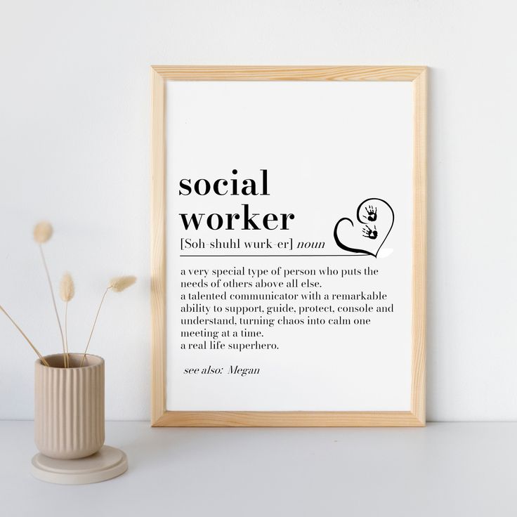 a white vase with some flowers in it next to a framed poster that says social worker