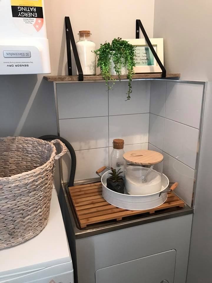 a washer and dryer in a small room with plants on the top shelf