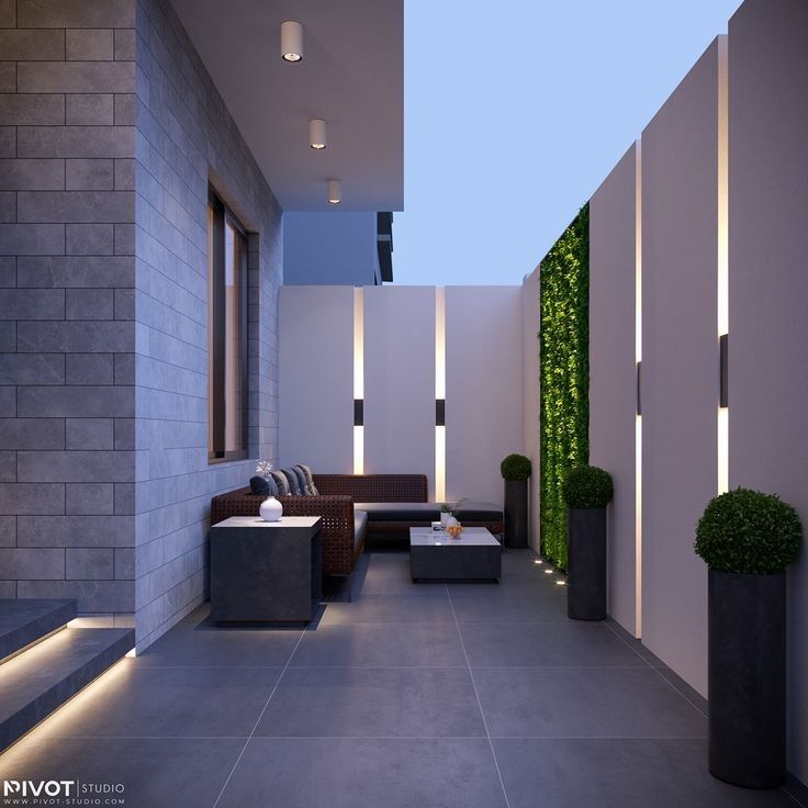 an outdoor living area with couches, tables and potted plants on the wall