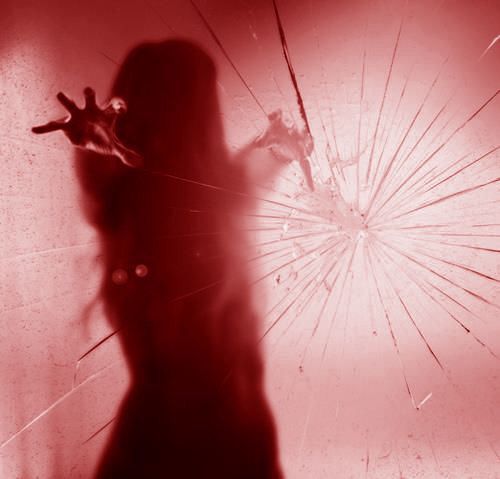 the shadow of a woman holding an umbrella in front of her face, with red light coming from behind it