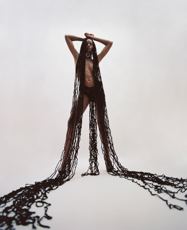 a woman with long black chains on her body standing in front of a white background