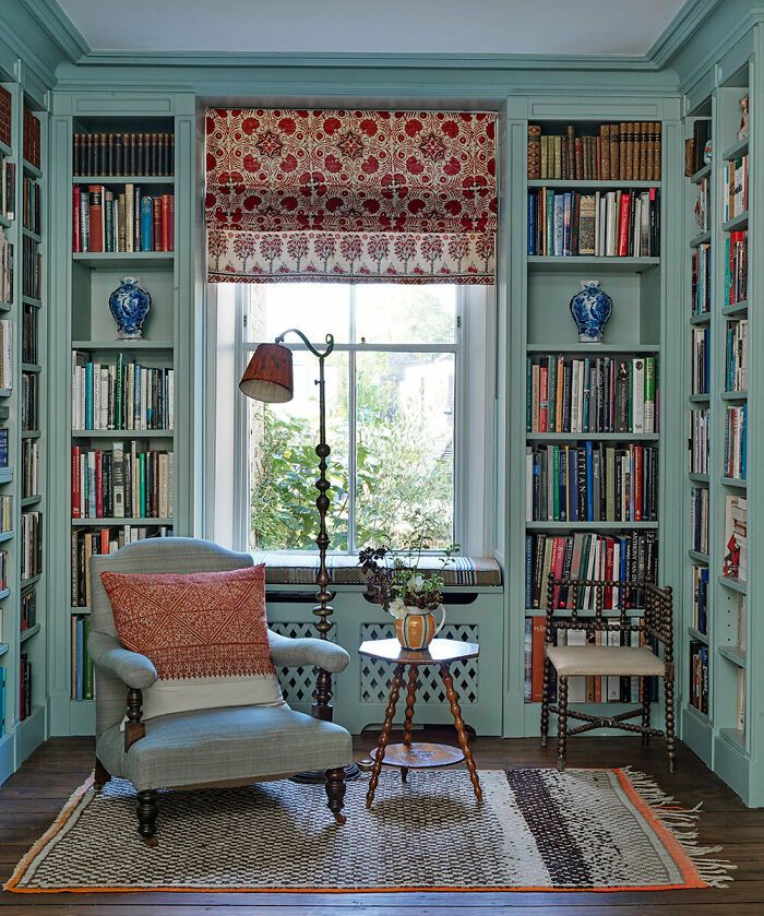 a living room filled with lots of bookshelves next to a table and chair