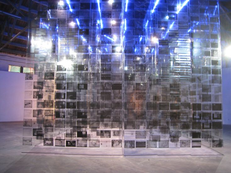 a large glass block with multiple images on it in the middle of a room filled with lights