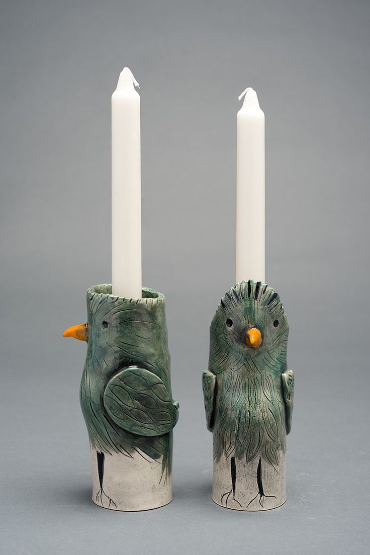 two candles with birds on them sitting next to each other