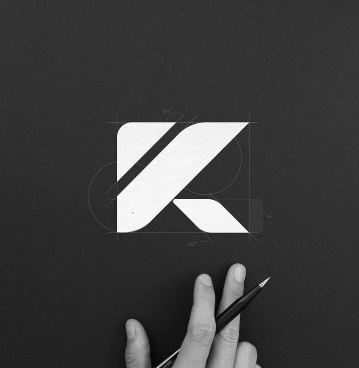 a person holding a pen and drawing on a piece of paper with the letter k in it