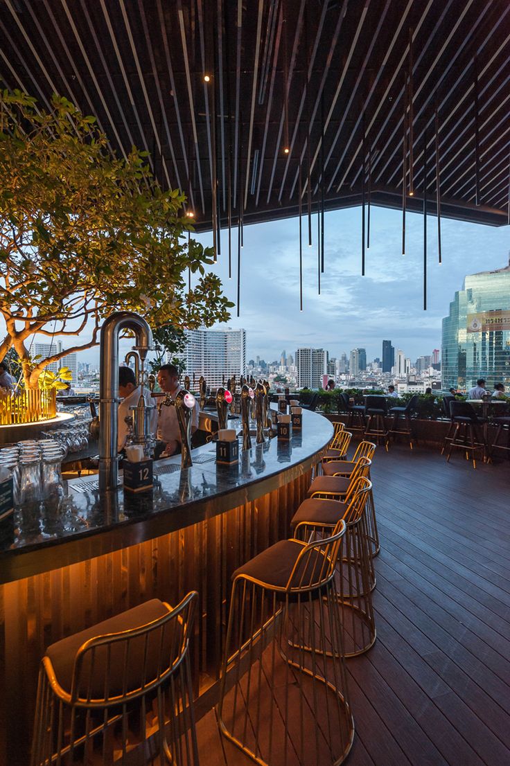 an outdoor bar with lots of chairs and tables in the middle of it at dusk