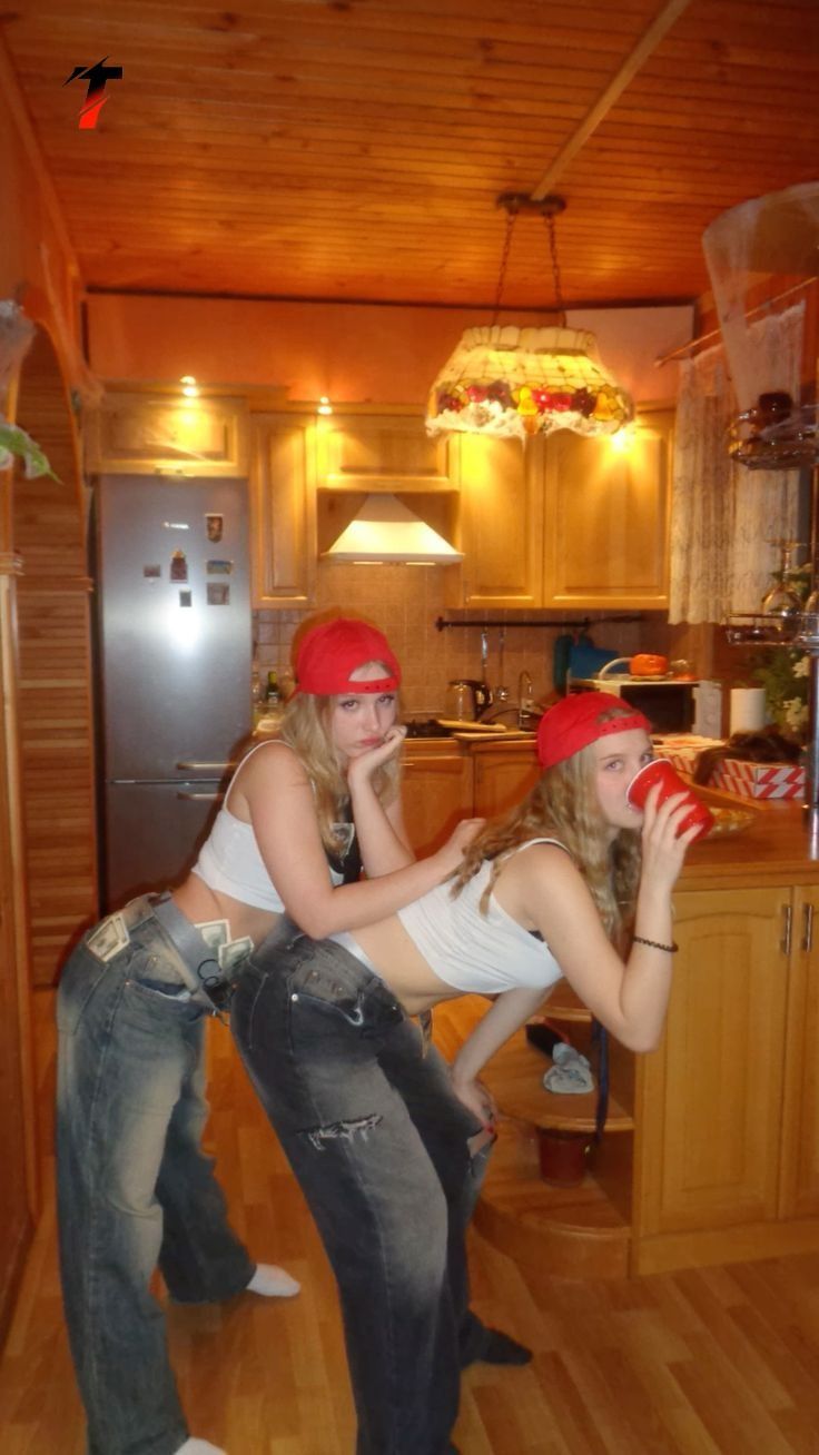 two young women in jeans and red bandanas drinking from cups while standing next to each other