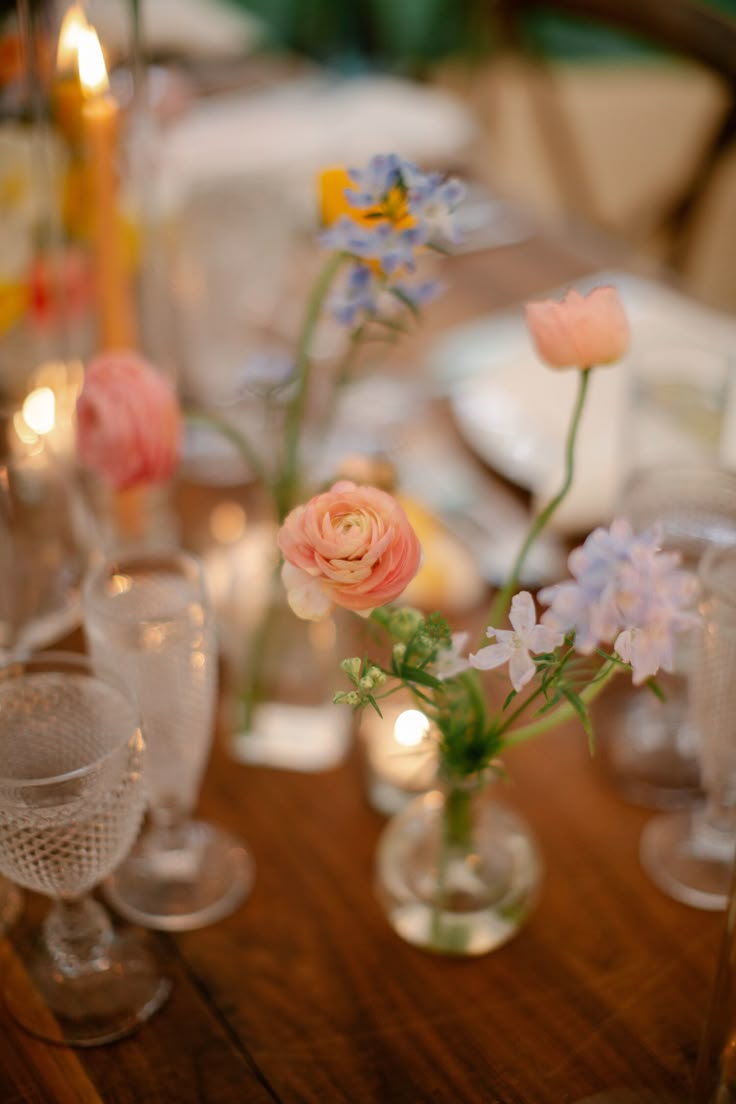 the table is set with flowers in vases and candles on top of each other