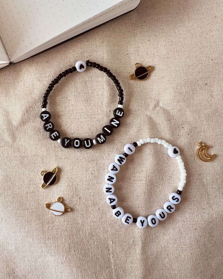 three different bracelets sitting on top of a bed next to an open notebook and pen