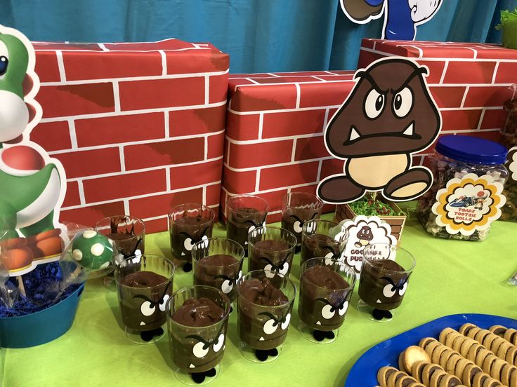 a table topped with cups filled with chocolate puddings and other dessert items next to a brick wall