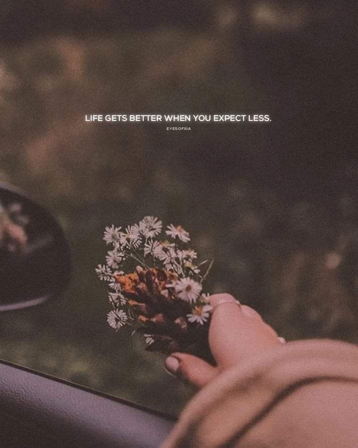 a person holding a flower in their hand next to a car mirror with the words life gets better when you expect less