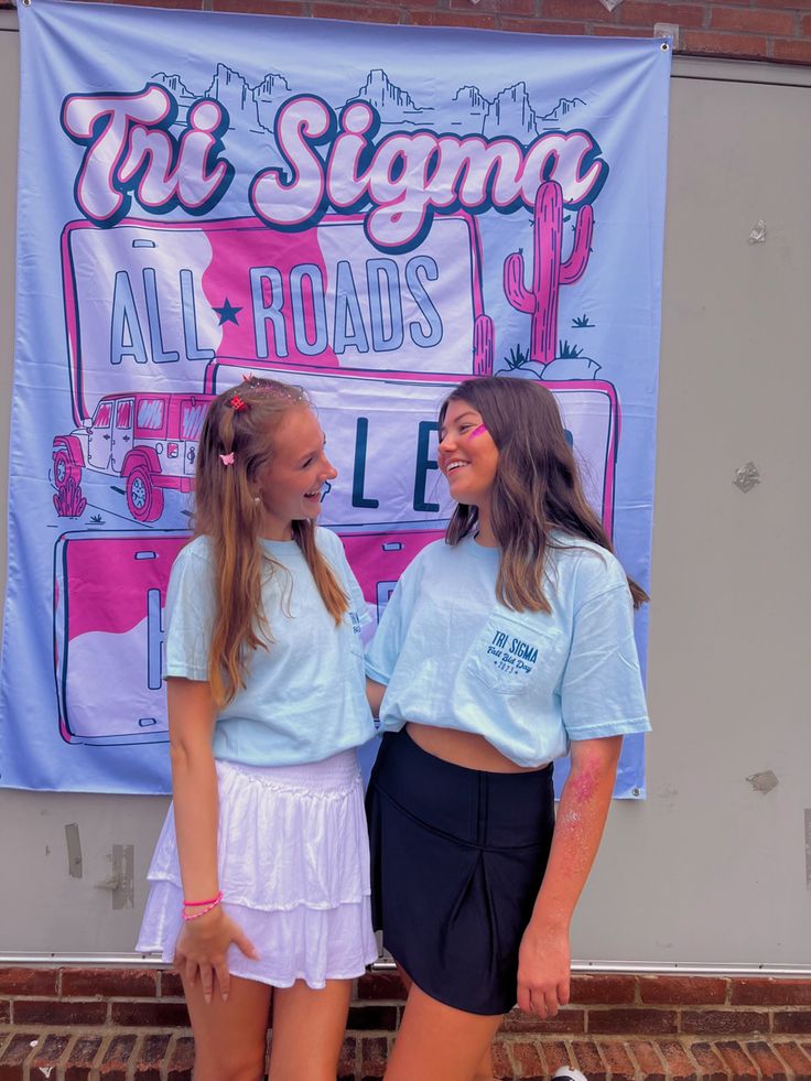 two girls standing next to each other in front of a sign