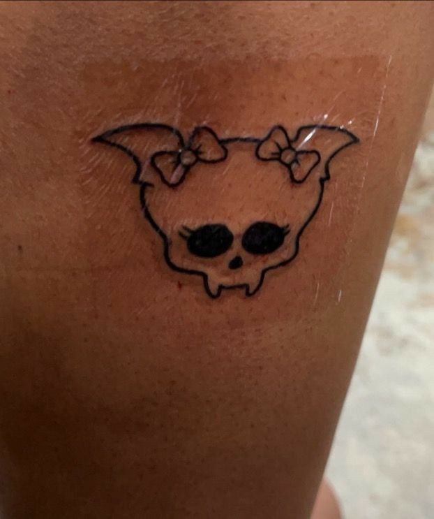 a woman's leg with a skull and bow tattoo on her left side thigh