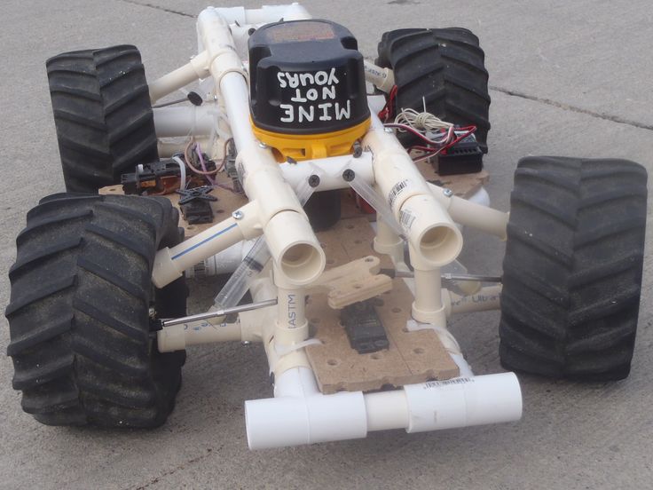 a white and black remote controlled vehicle on concrete ground with wheels attached to it's sides