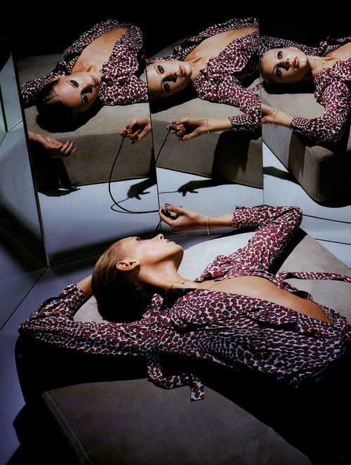 a woman laying on top of a couch in front of mirrors with her eyes closed