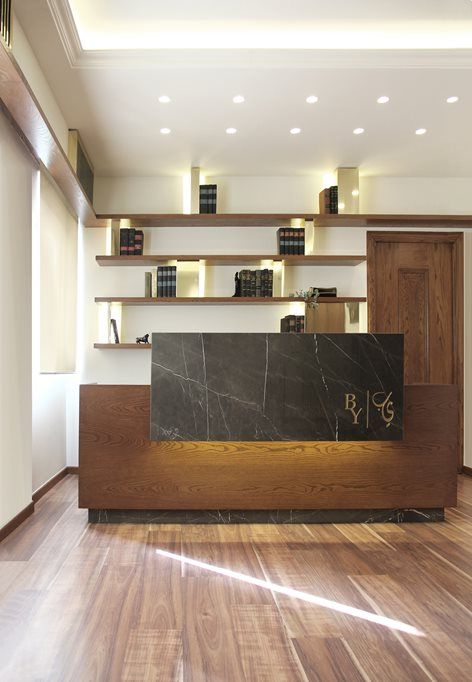 the front desk of a hotel lobby with wooden floors and shelving units behind it