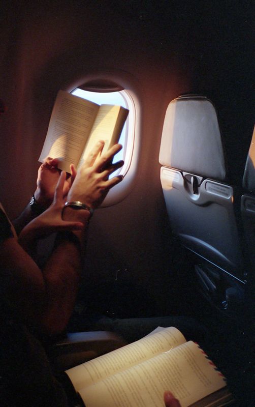 a person reading a book while sitting on an airplane