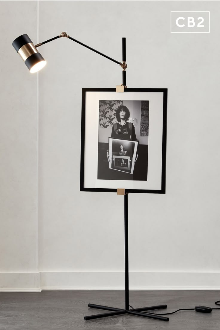 a black and white photo on a stand with a lamp next to it in the corner