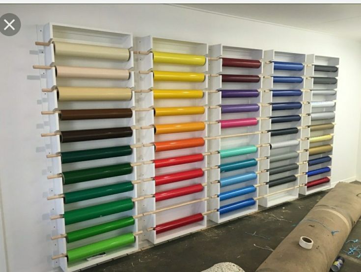 a room filled with lots of different colored rolls of paper next to a large wall