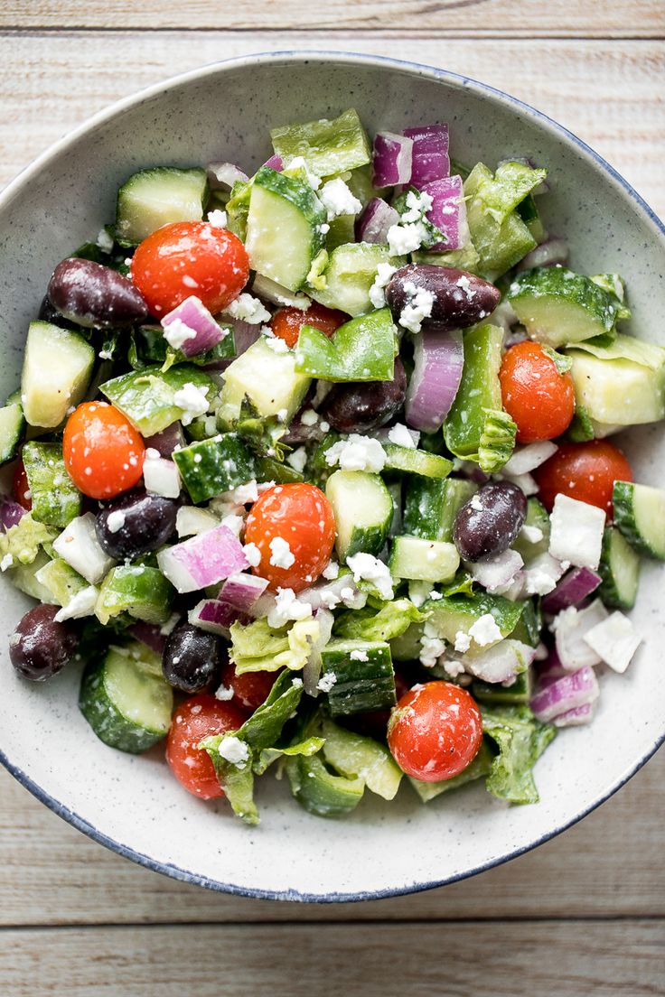 a salad with cucumbers, tomatoes, olives and feta cheese in a bowl