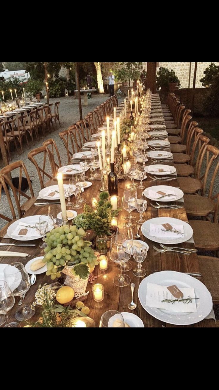 a long table is set up with candles and place settings for an outdoor dinner party