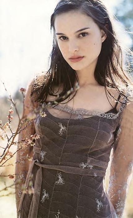 a beautiful young woman standing in front of a tree wearing a brown dress and posing for the camera