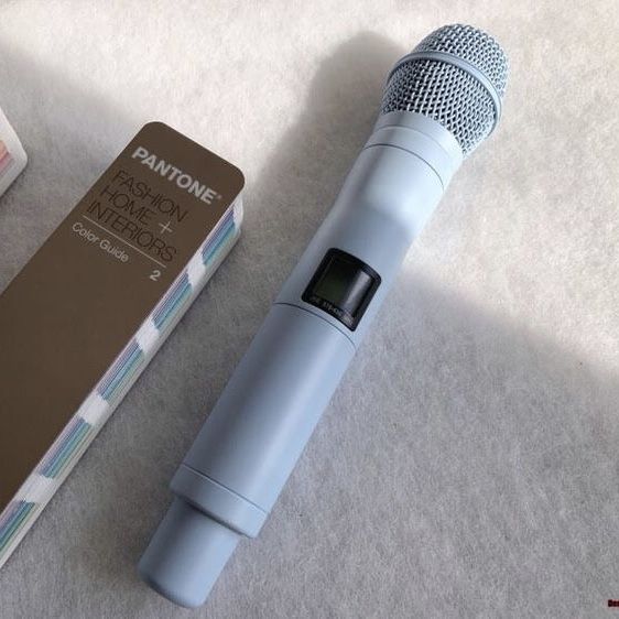 a blue microphone sitting on top of a white carpet next to a box and remote control