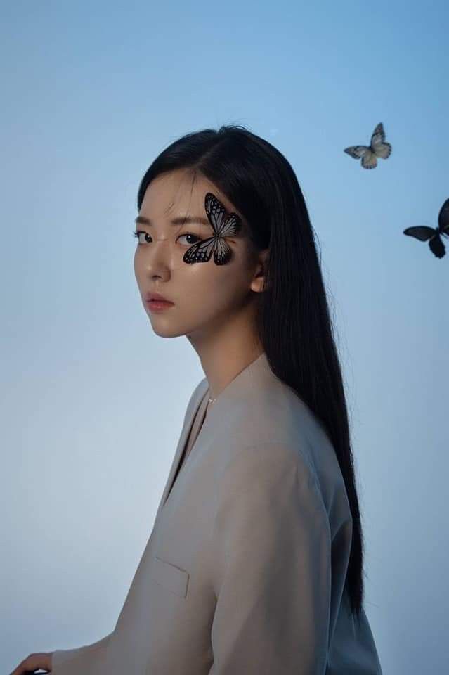 a woman with butterflies painted on her face in front of a blue sky and birds flying overhead