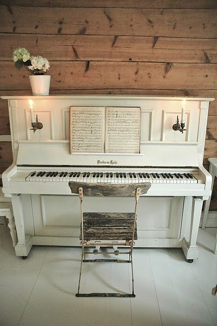 a white piano sitting in front of a wooden wall