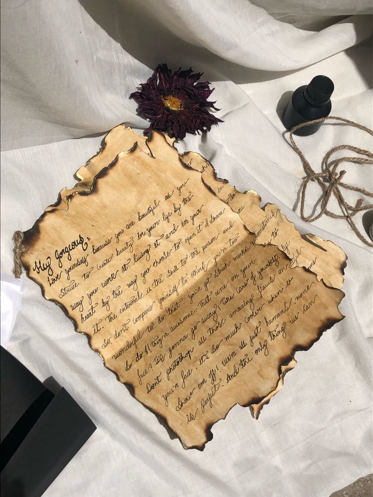 an old piece of paper with writing on it next to a flower and other items