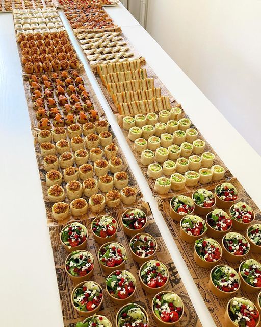 several trays filled with food sitting on top of a white table next to each other