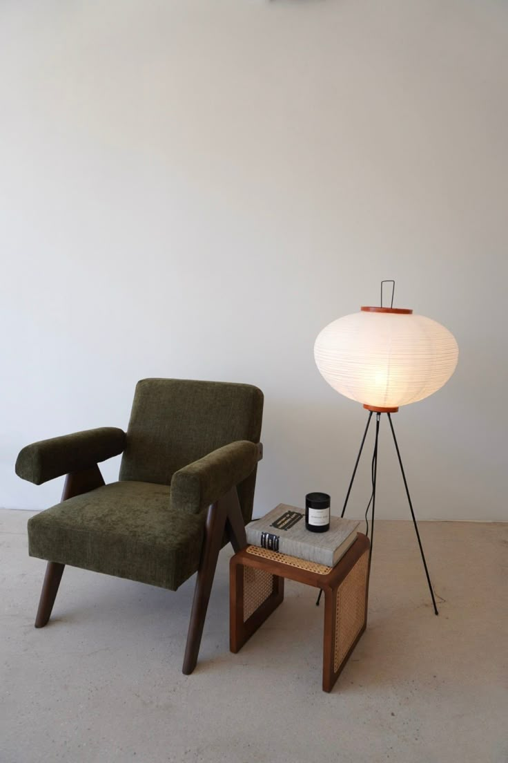 a green chair sitting next to a table with a lamp on it's side