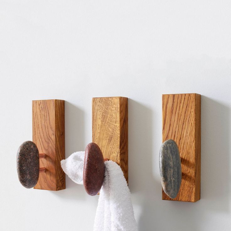 a towel is hanging on the wall next to two wooden hooks with rocks in them