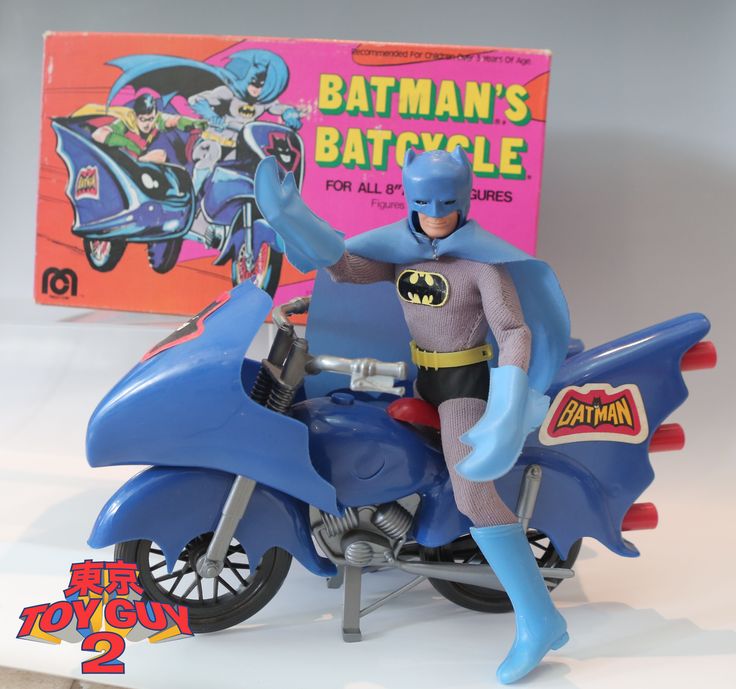 a toy batman riding on the back of a blue motorcycle