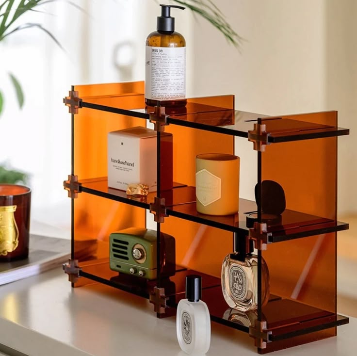 an orange shelf with bottles and soaps on it next to a potted plant