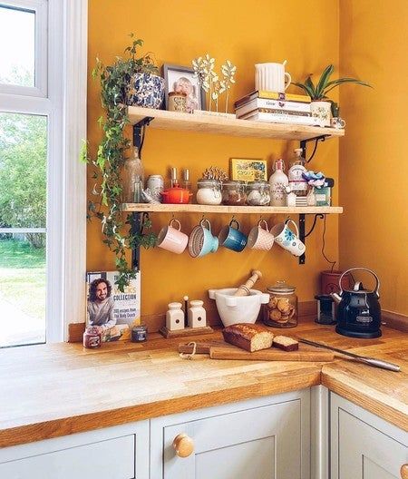 a kitchen with yellow walls and wooden counter tops, coffee mugs on the shelves